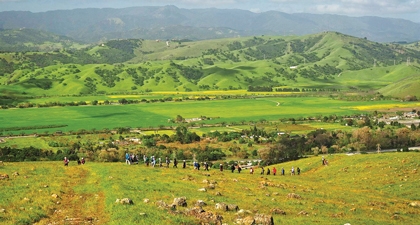 Line of hikers walking along Coyote Ridge with view of green Coyote Valley below
