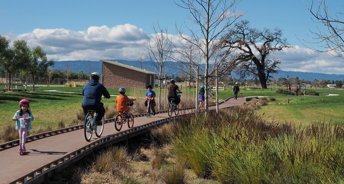 Family on bikes riding through Martial Cottle Park