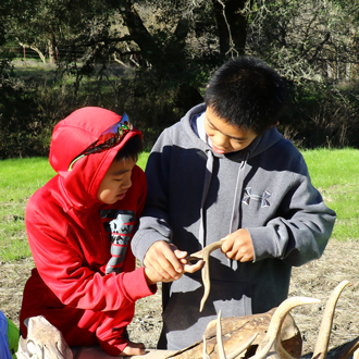 Two students examining a deer antler outside
