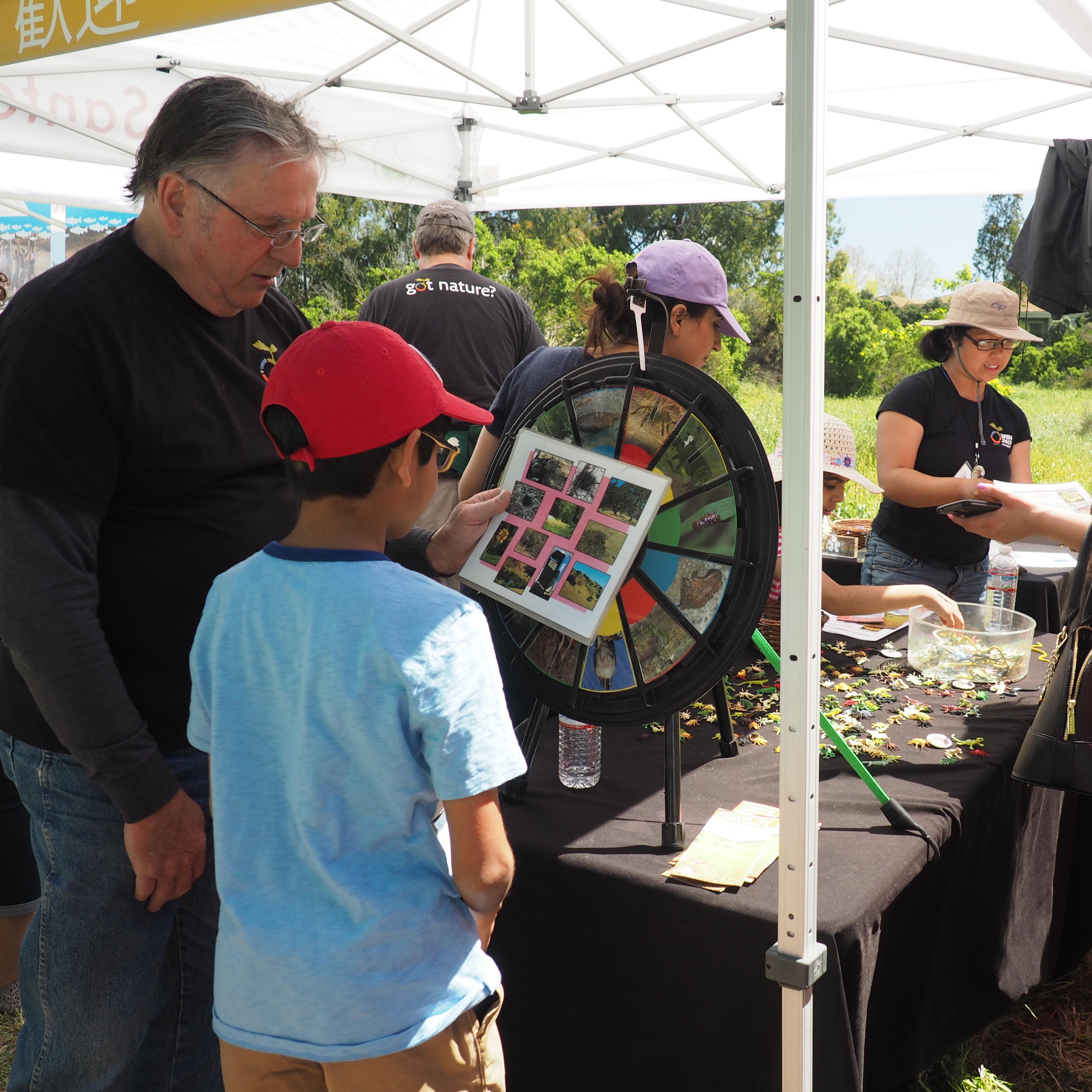 Male volunteer showing child nature game at booth